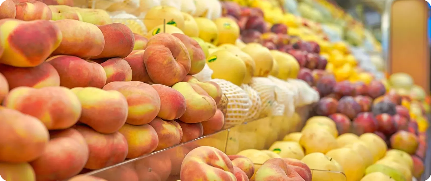 WPS Fresh Retail | Fresh Produce Supply | Consistent Availability Fresh peaches and apples displayed in a grocery produce section, representing WPS Fresh’s retail produce supply.